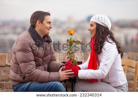 Romantic young man giving flower to his girlfriend