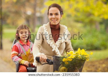 Young mother riding a bicycle with her daughter on a back seat