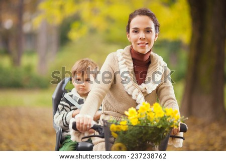 Mother riding a bicycle with her son sitting on the rear bike rack