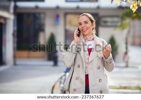 Smiling young woman on the street talking on the phone