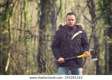Young man standing in the forest holding axe