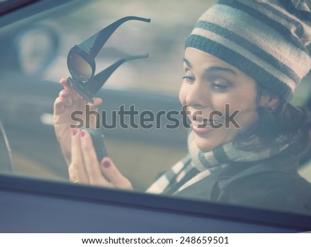 Happy young woman driving a car and using mobile phone