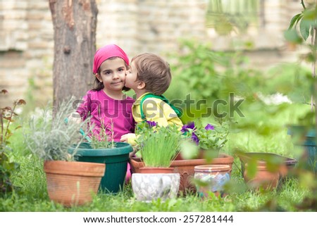 Little boy giving a kiss to his sister while playing in a garden