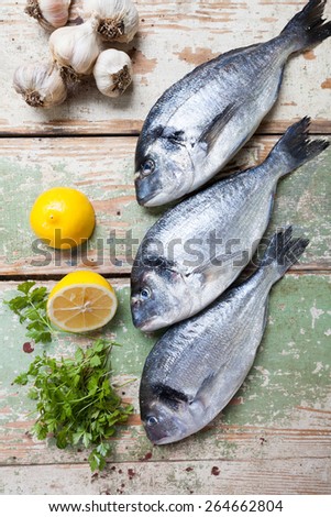 Three big fish (Sparus aurata) freshly caught on a wooden board