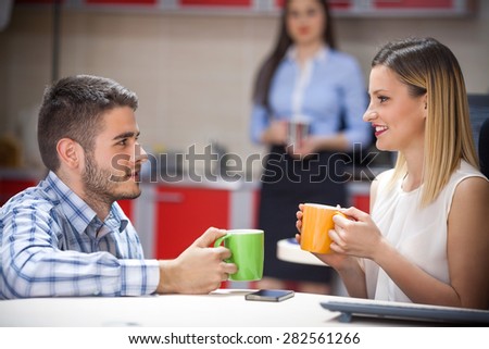 Young business person drinking coffee with a colleague in an office