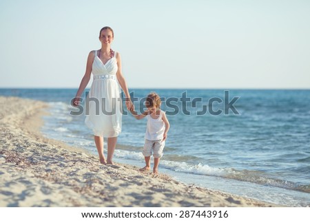 Happy young mother and her son walking by the sea