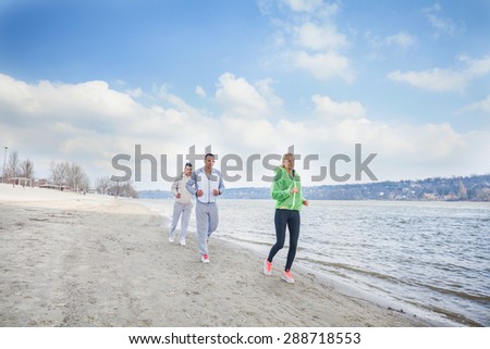 Three young people running by the river