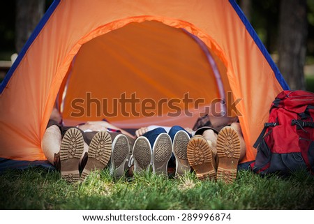 Four hikers wearing hiking boots and sneakers lying down inside a dome tent