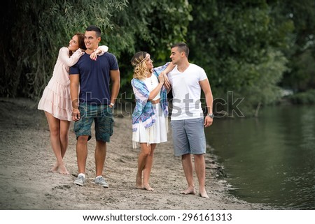Two young couple in love on a double date walking along the river