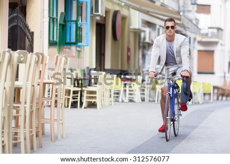 Handsome young businessman traveling to work by bicycle in the city