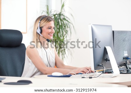 Portrait of smiling young woman working on a computer in a call center