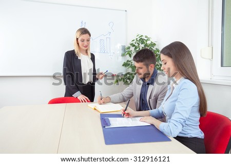 Young business people writing notes on a training class or seminar in a conference room