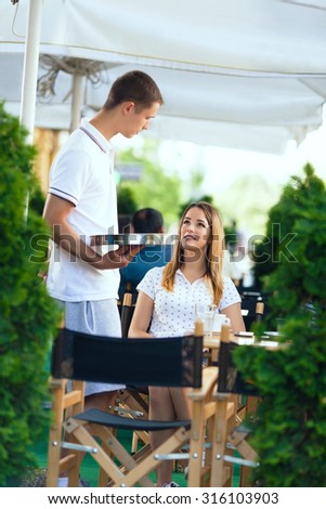 Waiter taking an order from a girl sitting in a sidewalk cafe
