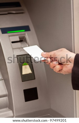 Person inserts credit card at an ATM (visible only hand of the person)