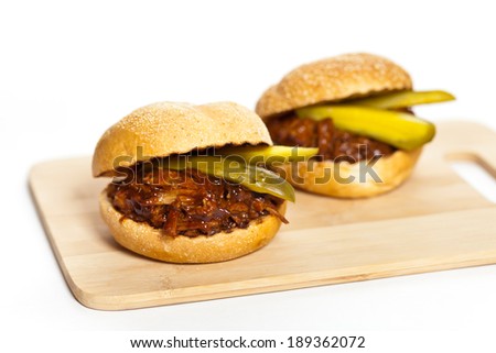 Pulled pork sandwich on a bun with two pickles. Selective focus.
