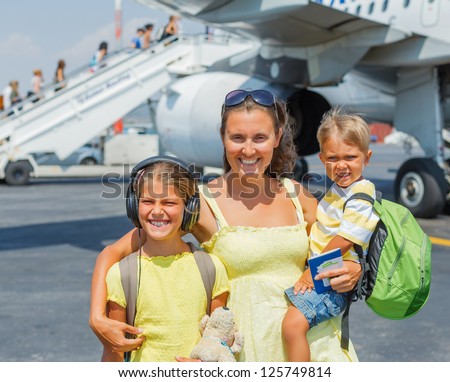 Young mother with two kids in front of airplane