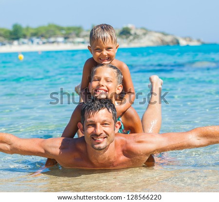 Family - father with his kids have fun and swim in the transparent sea