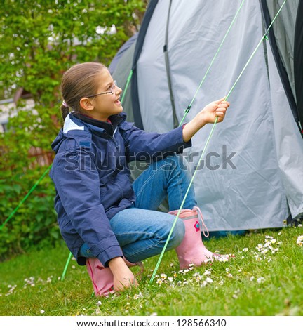 Young girl out camping learning how to pitch tent