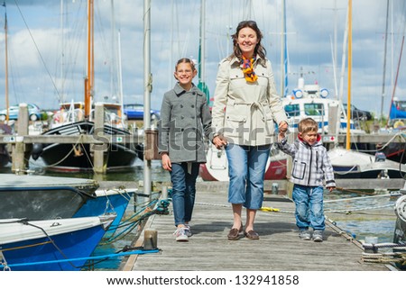 Young happy family of three rests on Yacht Club and is glad at life.