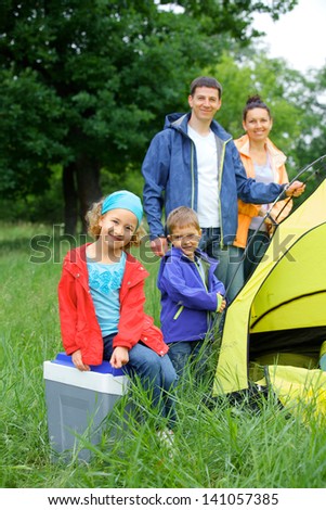 Young girl with her family near tent in camping on the nature