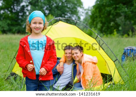Young girl with his family near tent in camping on the nature