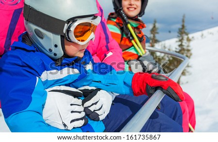 Portrait of happy girl in ski goggles and a helmet with his sister on the ski lift