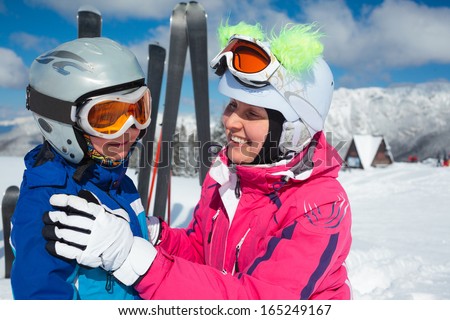 Happy little boy to ski in ski goggles and a helmet with his mother