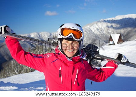Young woman ski goggles and a helmet holding ski in the mountains