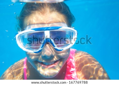 Close-up underwater portrait of the cute girl swimming and smiling