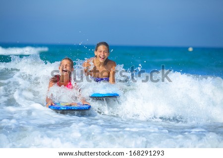 Summer vacation - Two cute girls having fun with surfboard in the ocean