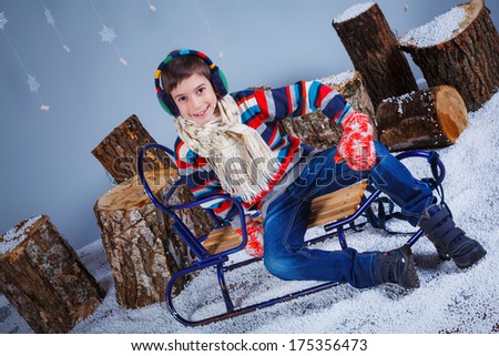 Winter Fashion. Adorable happy fashion boy in winter hat gloves and sweater in studio.