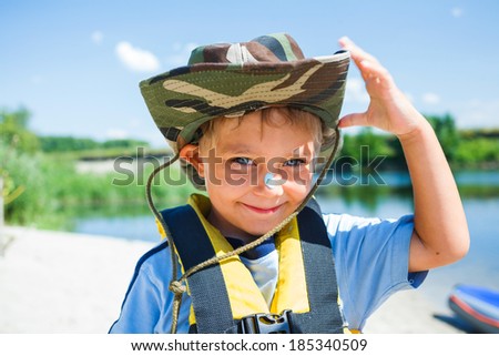 Ready kayaking. Portrait of happy little boy near the river and enjoying a lovely summer day