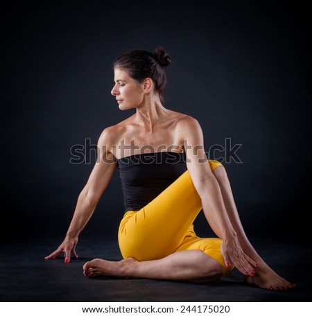 Pretty brunette woman doing yoga. Shot on black background