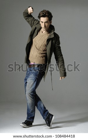 young casual man full body walking over gray background