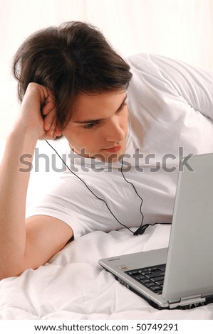 Portrait of a smiling man with laptop lying in the bed