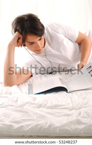 Attractive young man reading a book in bed