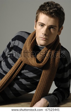 Portrait of a young man sitting wearing scarf on the floor