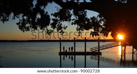 people silhouetted at sunset on fishing dock florida usa
