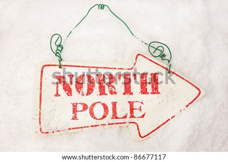 A white sign showing the way to the north pole sat in snow