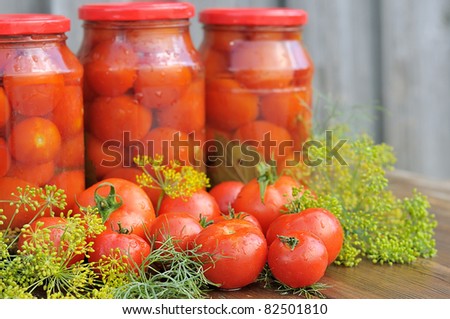 Fresh tomatoes. Canned tomatoes. tomatoes in a glass jar on a wooden table.