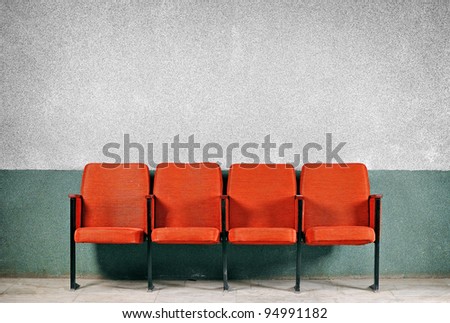 Orange seats from the old gray walls. A number of four seats. Chairs against the wall.