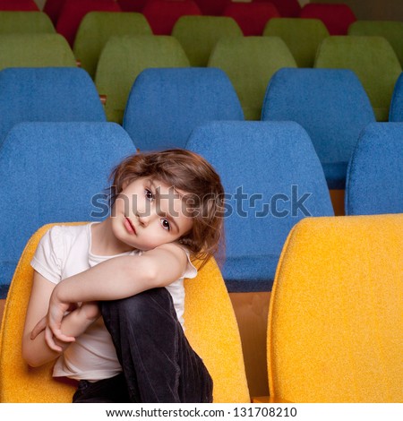 cute pretty little girl sitting in the cinema hall