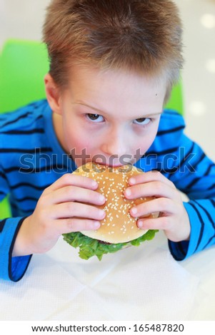 handsome little boy eating burger