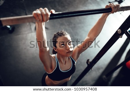 Cute young muscular girl doing pull-ups exercise at the gym.  商業照片 © 