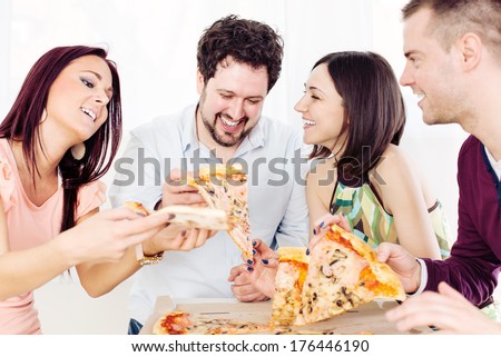 Group of happy friends sitting and eating pizza at Home Interior.