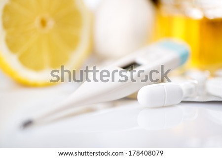 Vitamins and pills for treatment Cold And Flu. Lemon, honey and Thermometer on white background. Selective focus. Focus on pill.