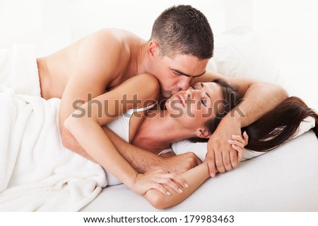 Young guy kissing his girl on the cheek for good morning in the bed.