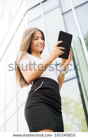 Happy Businesswoman standing on the street in front of Office Building and using a Tablet PC.