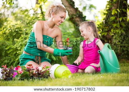 Beautiful mother and daughter planting flowers in the garden.