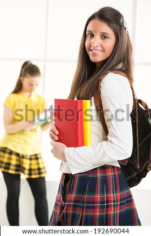 Happy beautiful teenage girl with Colorful books and school bag